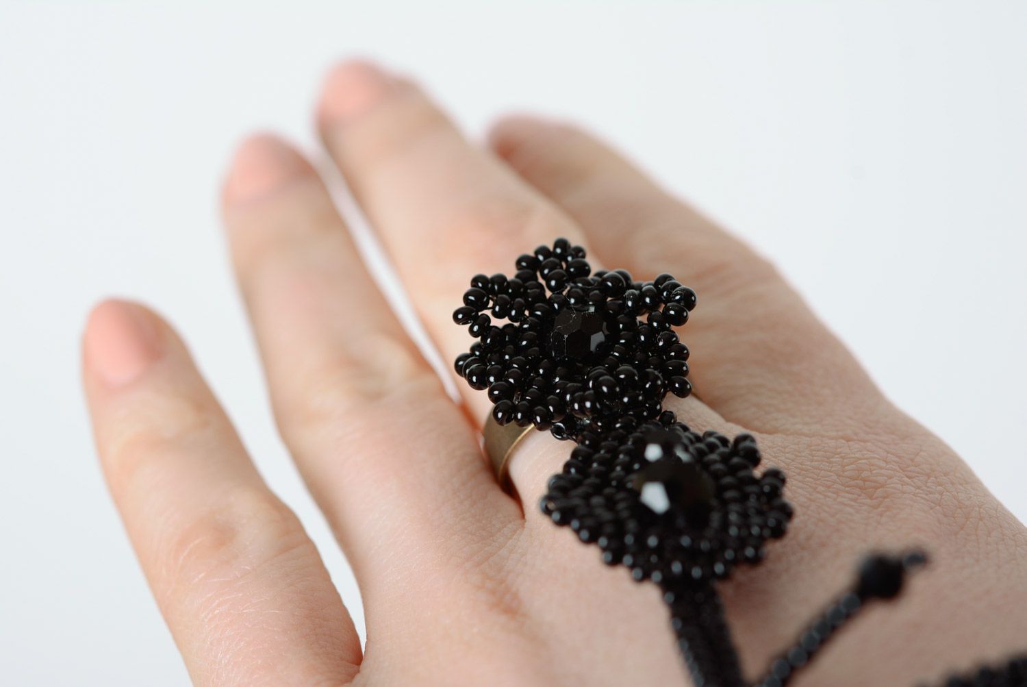Schwarzes originelles handgemachtes Slave Armband aus Glasperlen auf Finger mit Blättern foto 3