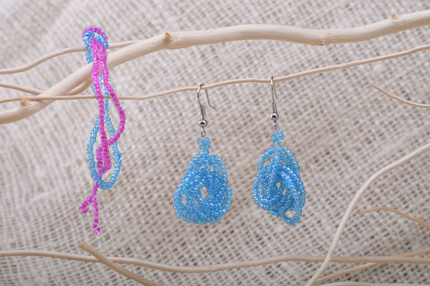 Set of handmade beaded jewelry long earrings and wrist bracelet on blue color photo 1