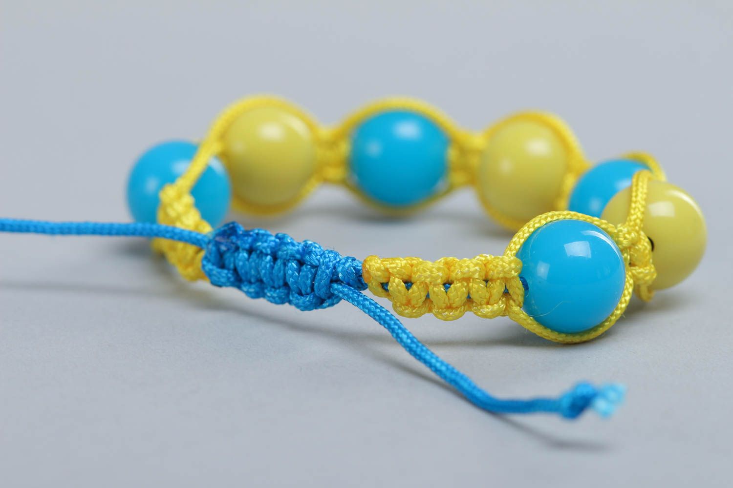 Handgemachtes blau gelbes Armband aus Textil Schnüren und Plastik Perlen  foto 4