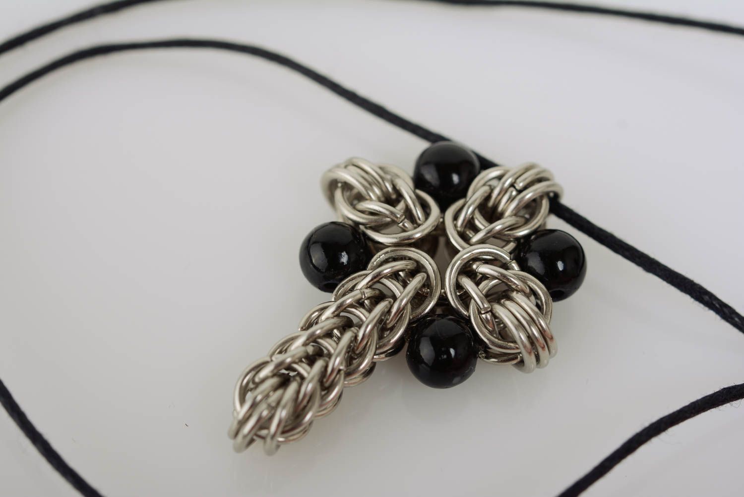 Pendentif croix en métal composée de mailles tressées et perles noires fait main photo 1