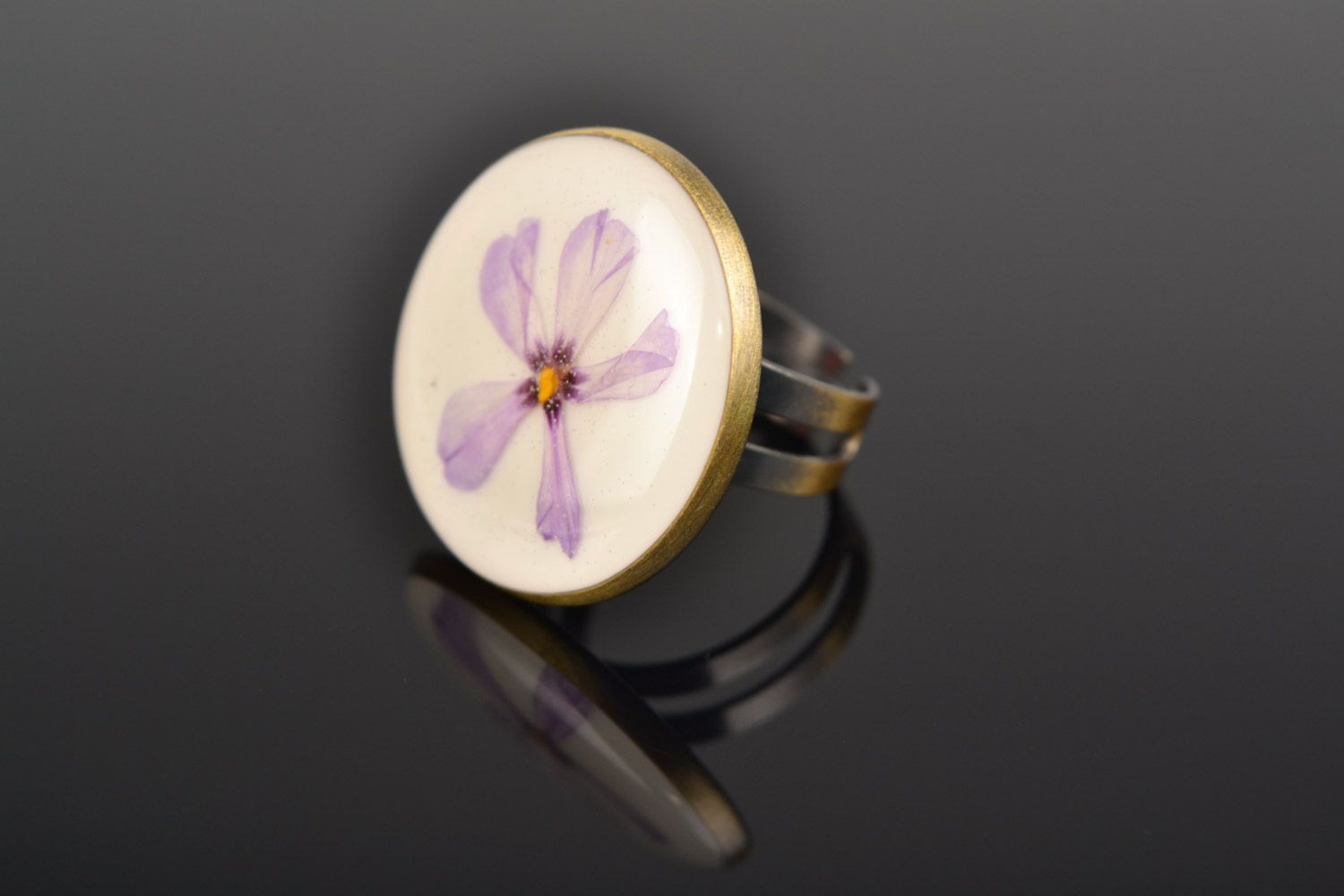 Handmade round ring with natural flowers on white background in epoxy resin photo 1