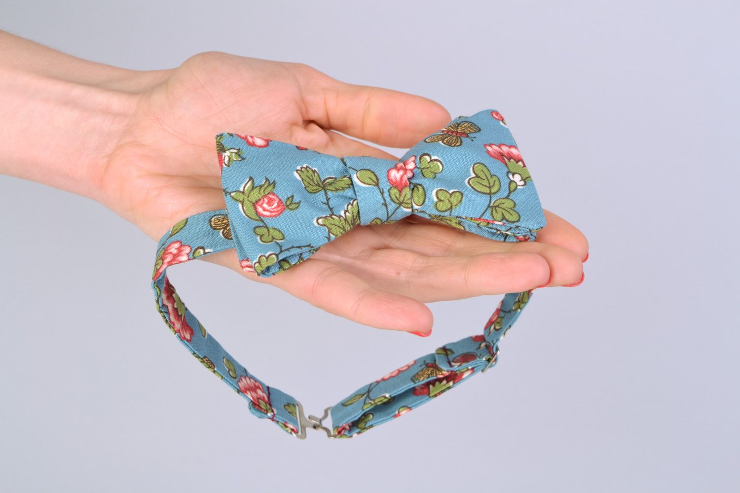 Handmade bow tie sewn of American cotton with flower pattern on blue background photo 2