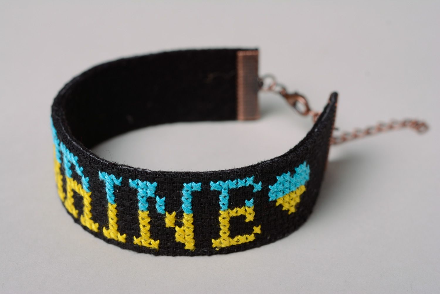 Handmade designer bracelet with embroidered lettering Ukraine on black background photo 2