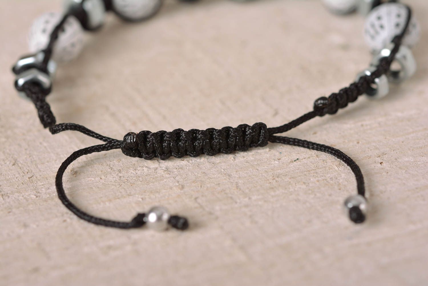 Strand black cord bracelet with white ceramic beads and female metal screws photo 4