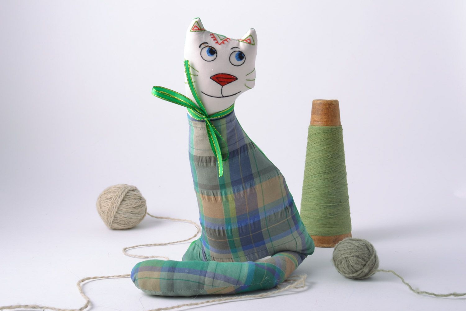 Handmade designer soft toy cat sewn of checkered fabric with green bow  photo 1