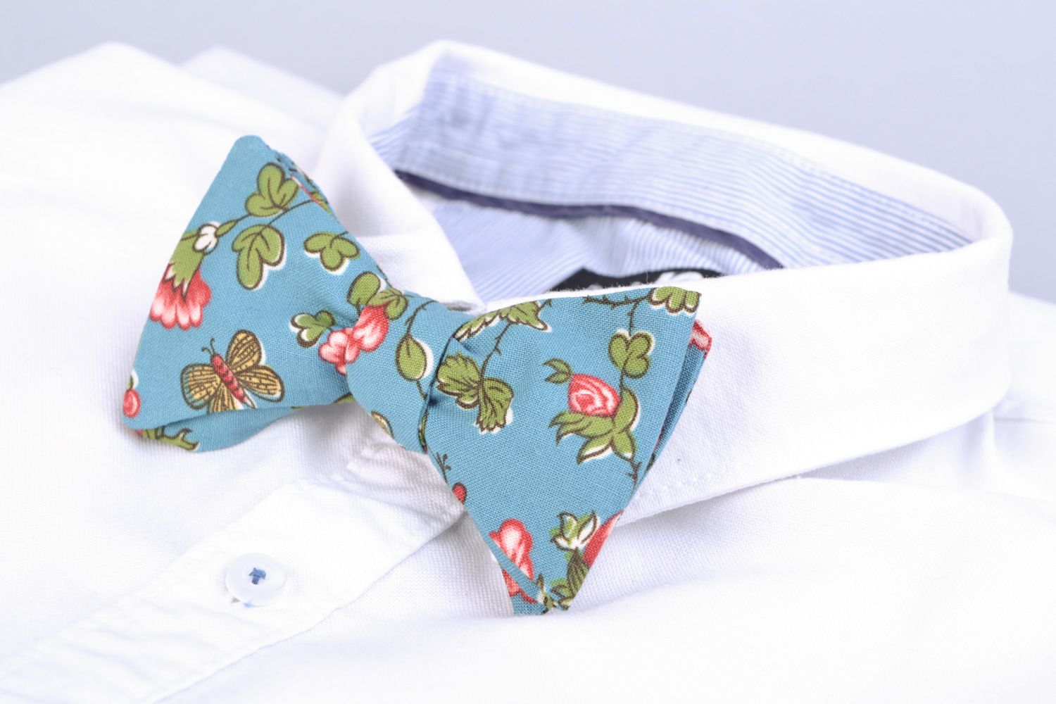 Handmade bow tie sewn of American cotton with flower pattern on blue background photo 1