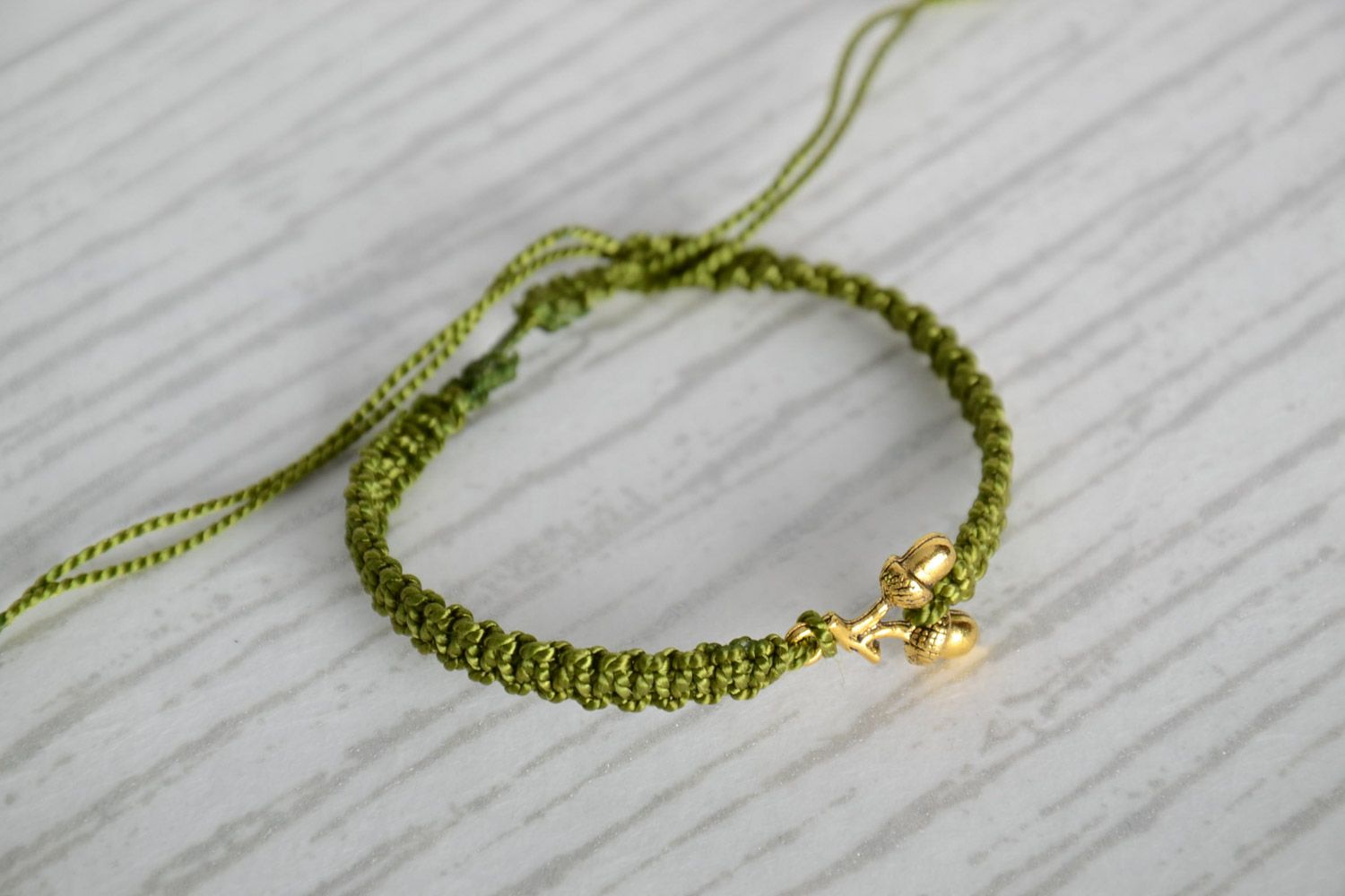 Women's handmade macrame woven thread bracelet of green color with metal charms in the shape of acorns photo 1