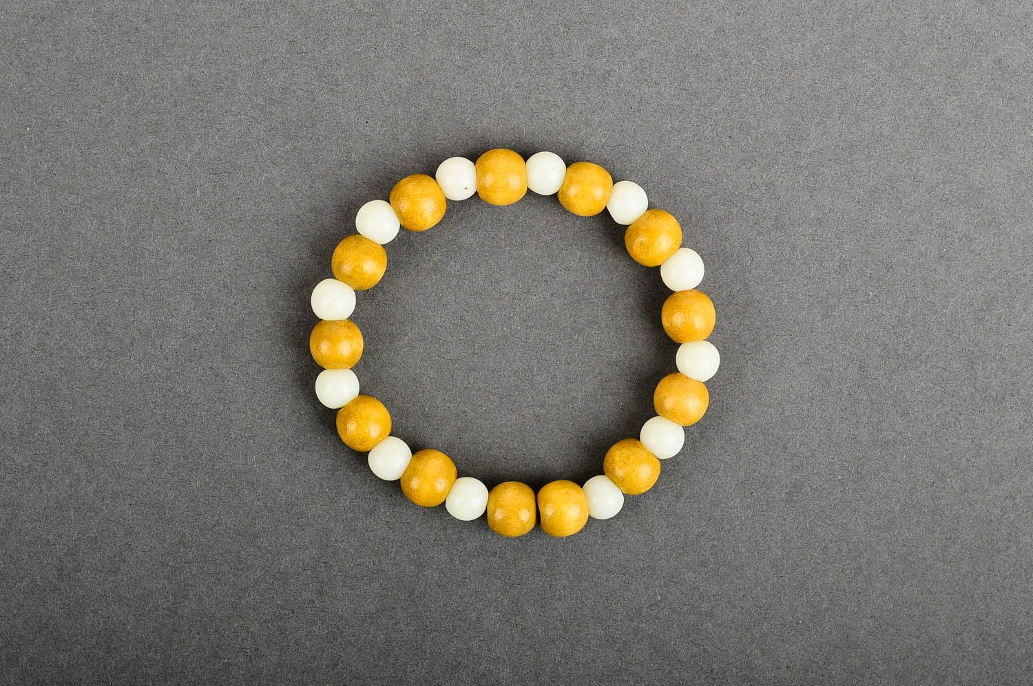 Stretchy beaded bracelet made of yellow wooden and white plastic beads photo 1