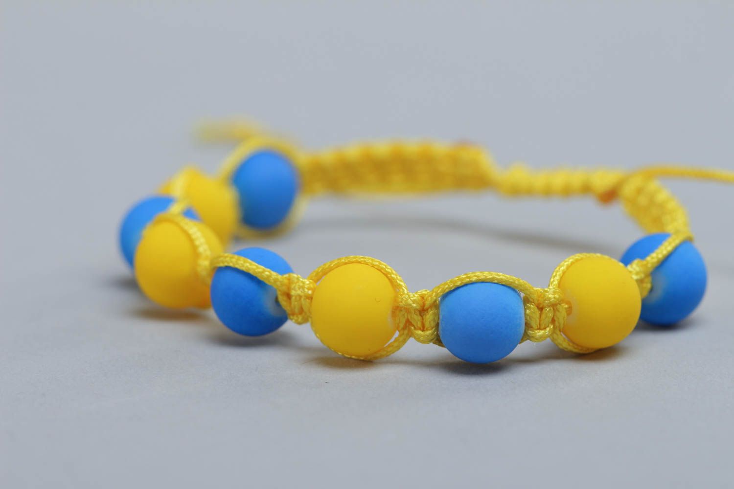 Pulsera artesanal  trenzada de hilos con cuentas plásticas azul y amarilla foto 1