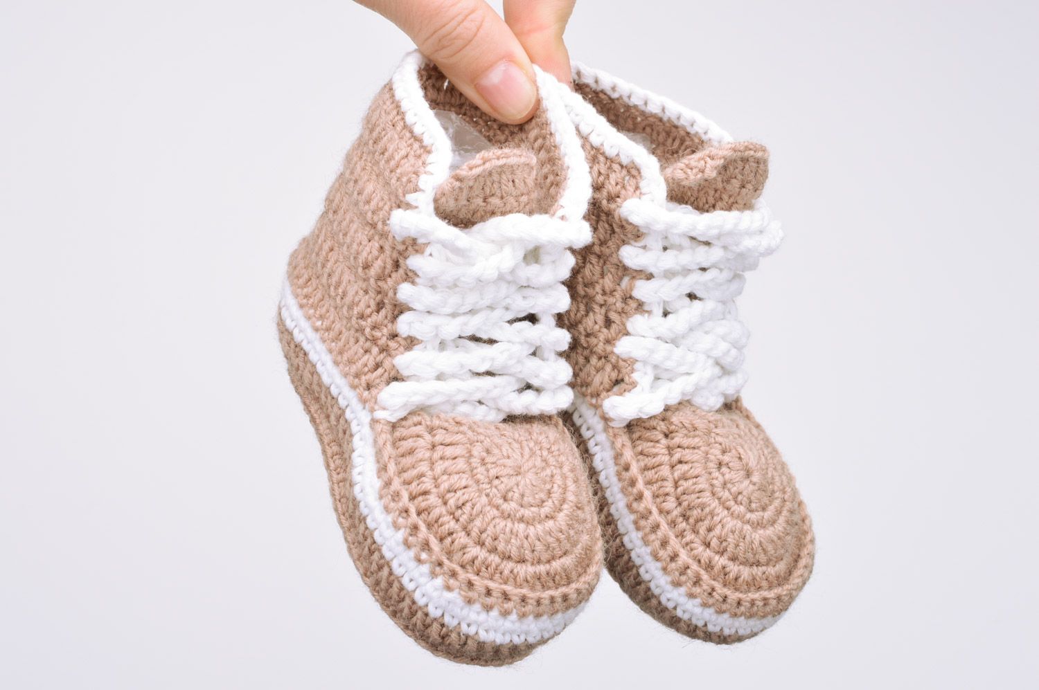 Originelle hellbraune gehäkelte Babyschuhe mit Schuhbändern in Form der Turnschuhen foto 3