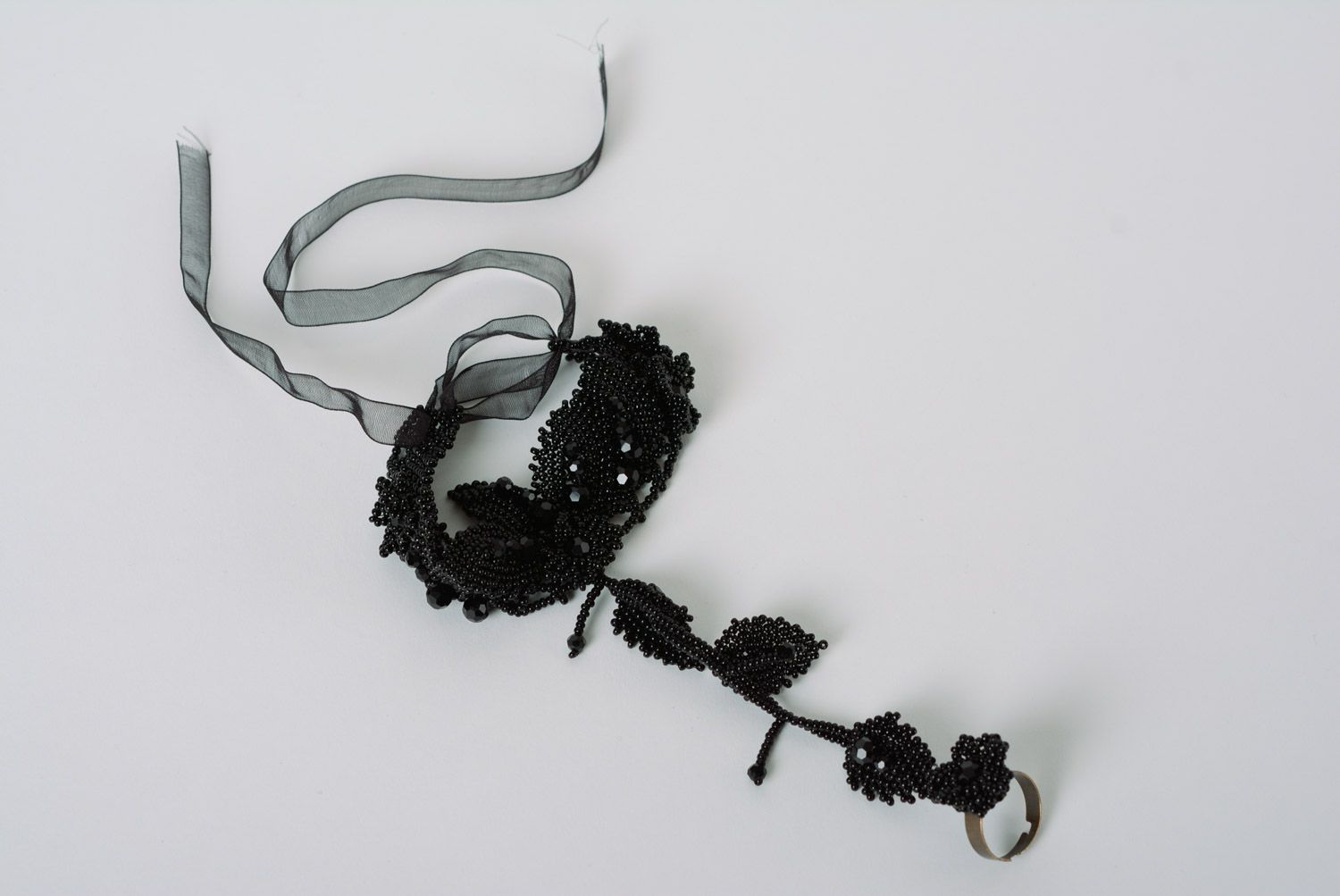 Schwarzes originelles handgemachtes Slave Armband aus Glasperlen auf Finger mit Blättern foto 2