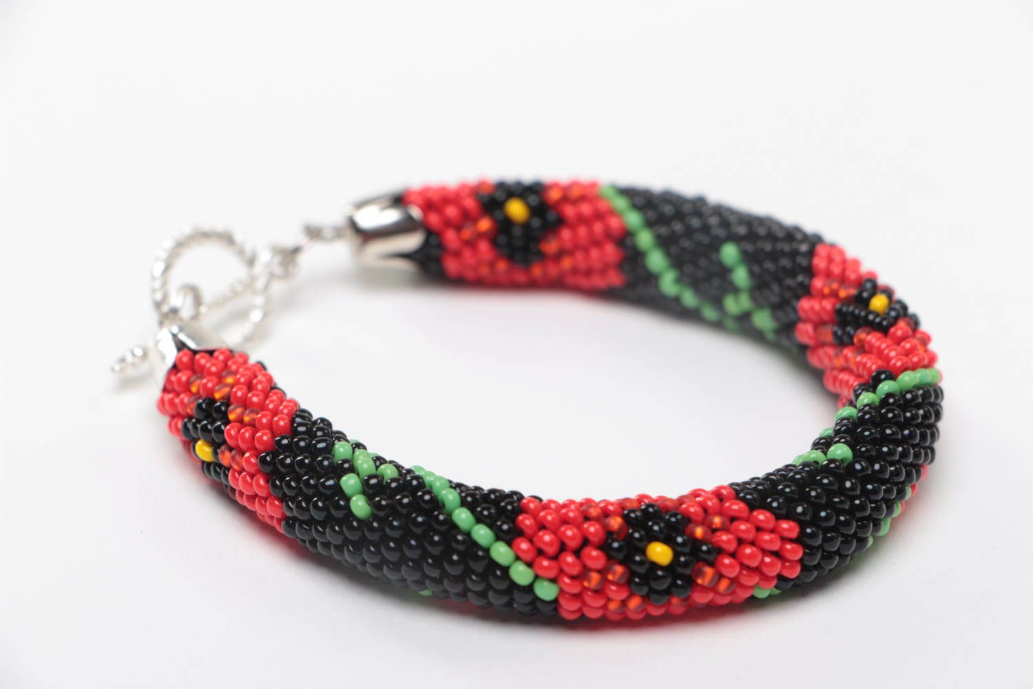 Handmade beaded cord bracelet with red floral pattern on black background photo 3