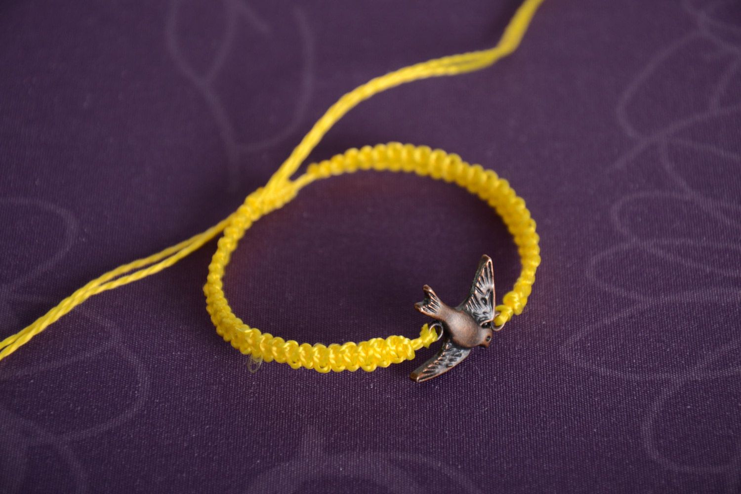 Handmade women's woven capron thread wrist bracelet of yellow color with metal bird charm photo 1