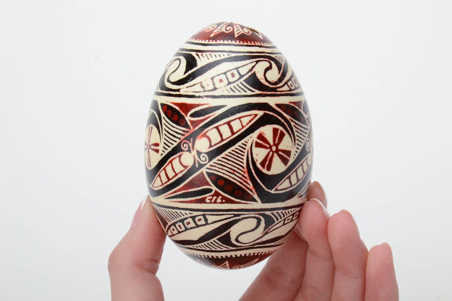 Handmade painted goose egg of black white and red colors ornamented using waxing technique photo 5