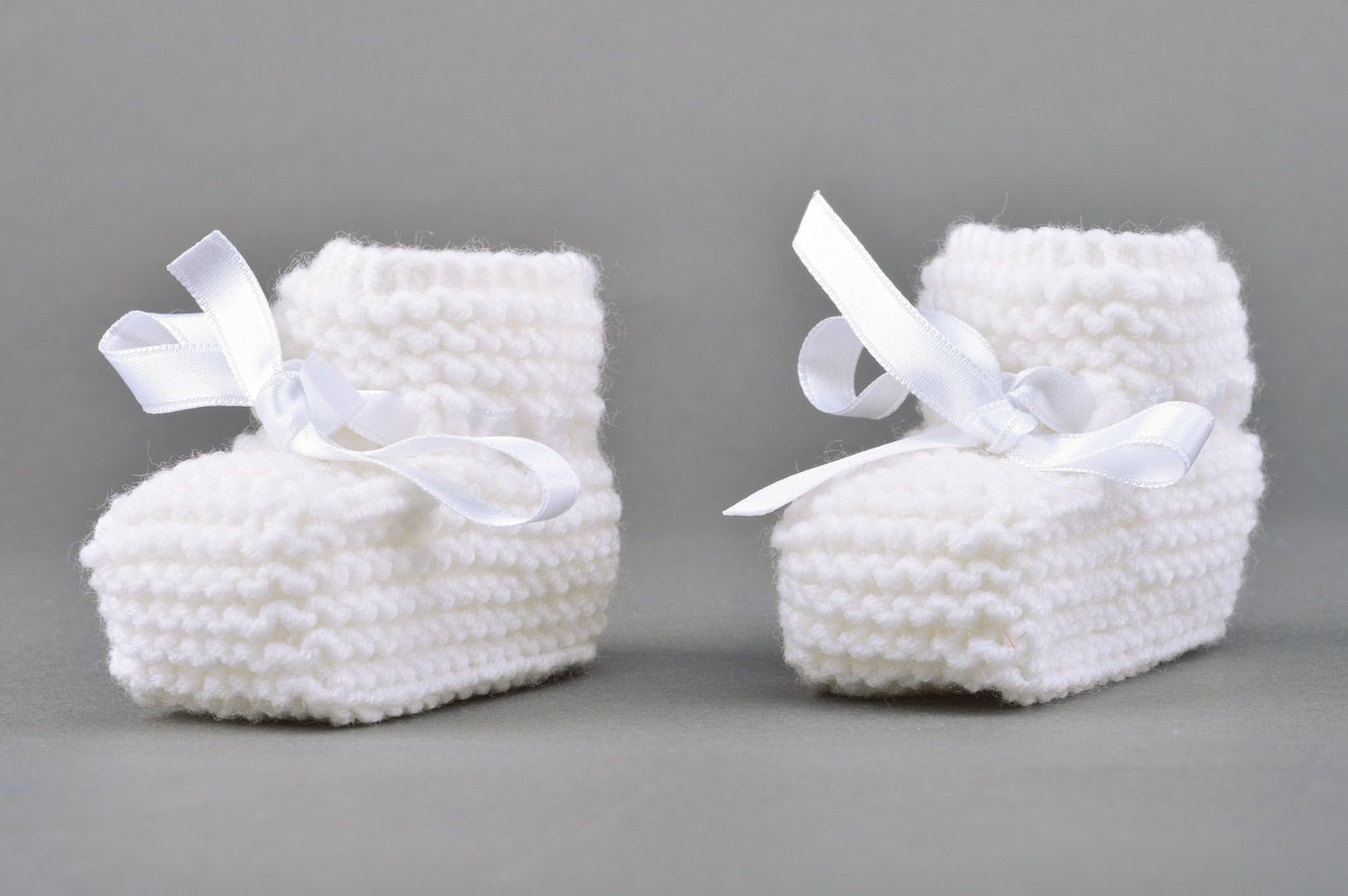 Handmade small knitted baby booties of white color with satin bow for girls photo 2