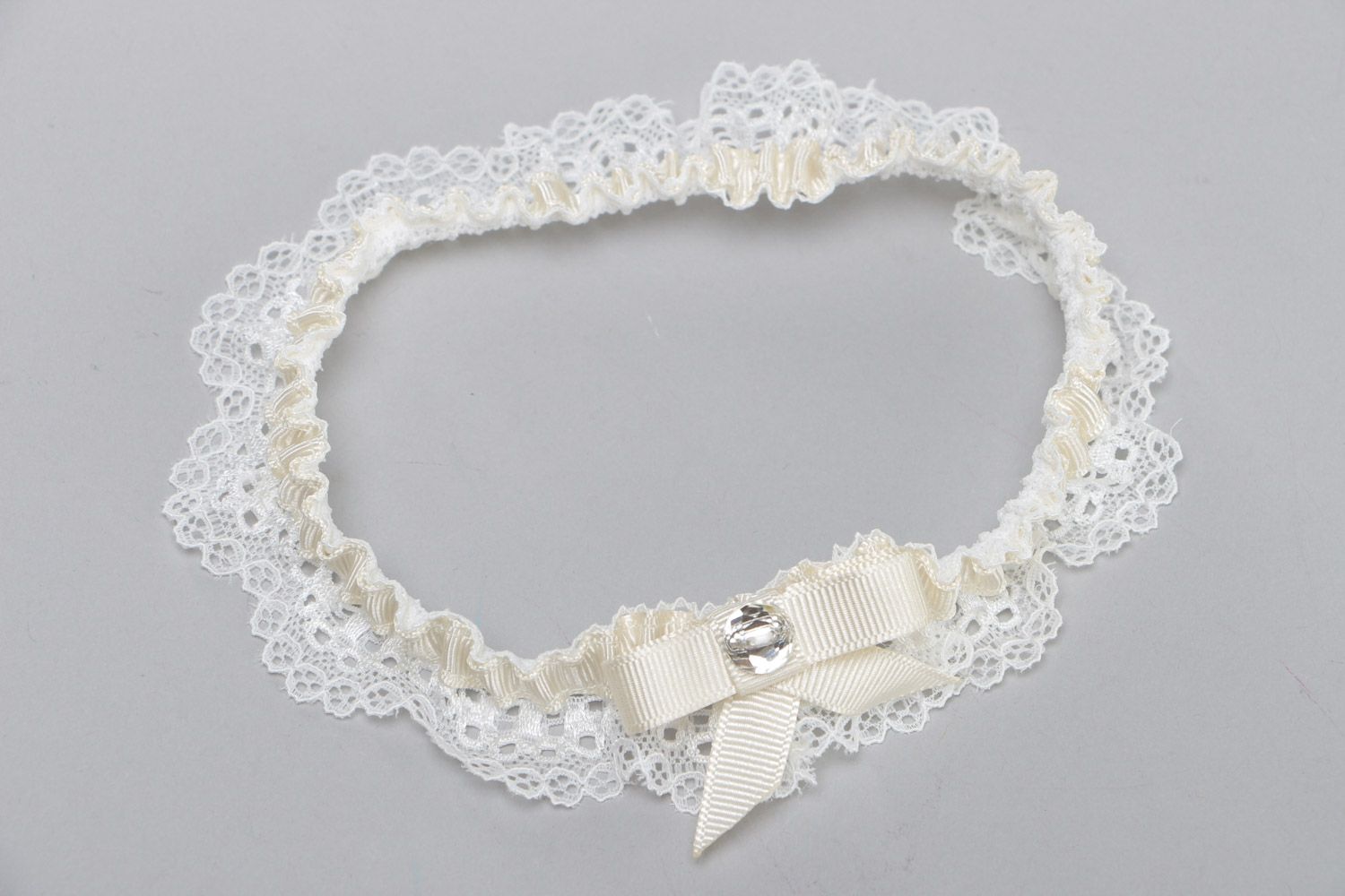 Handgemachtes weißes Strumpfband für Hochzeit aus Spitze und Ripsbändern mit Glasperle foto 2
