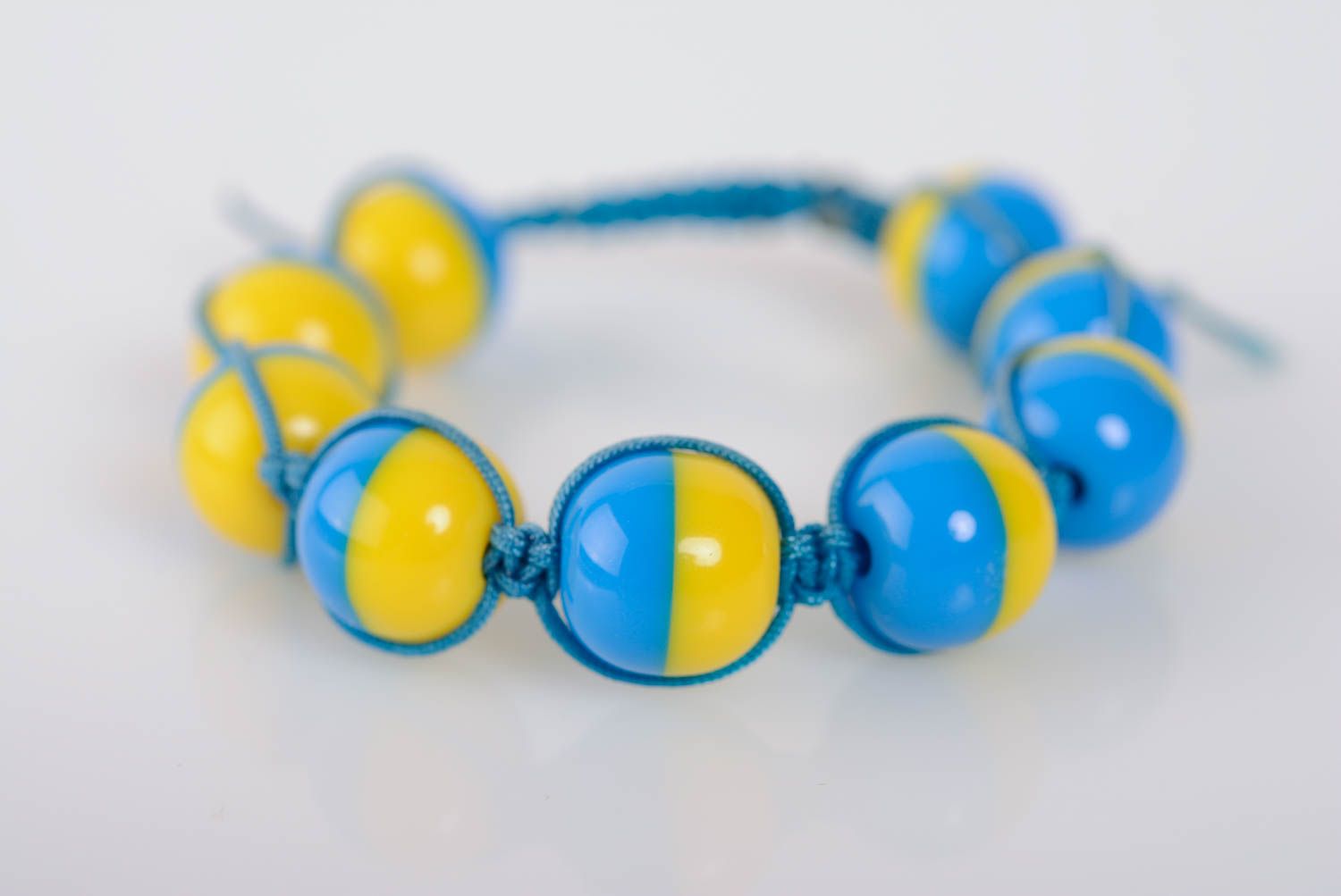 Künstlerisches dünnes buntes Armband aus Plastik und Schnur in Blau und Gelb foto 1