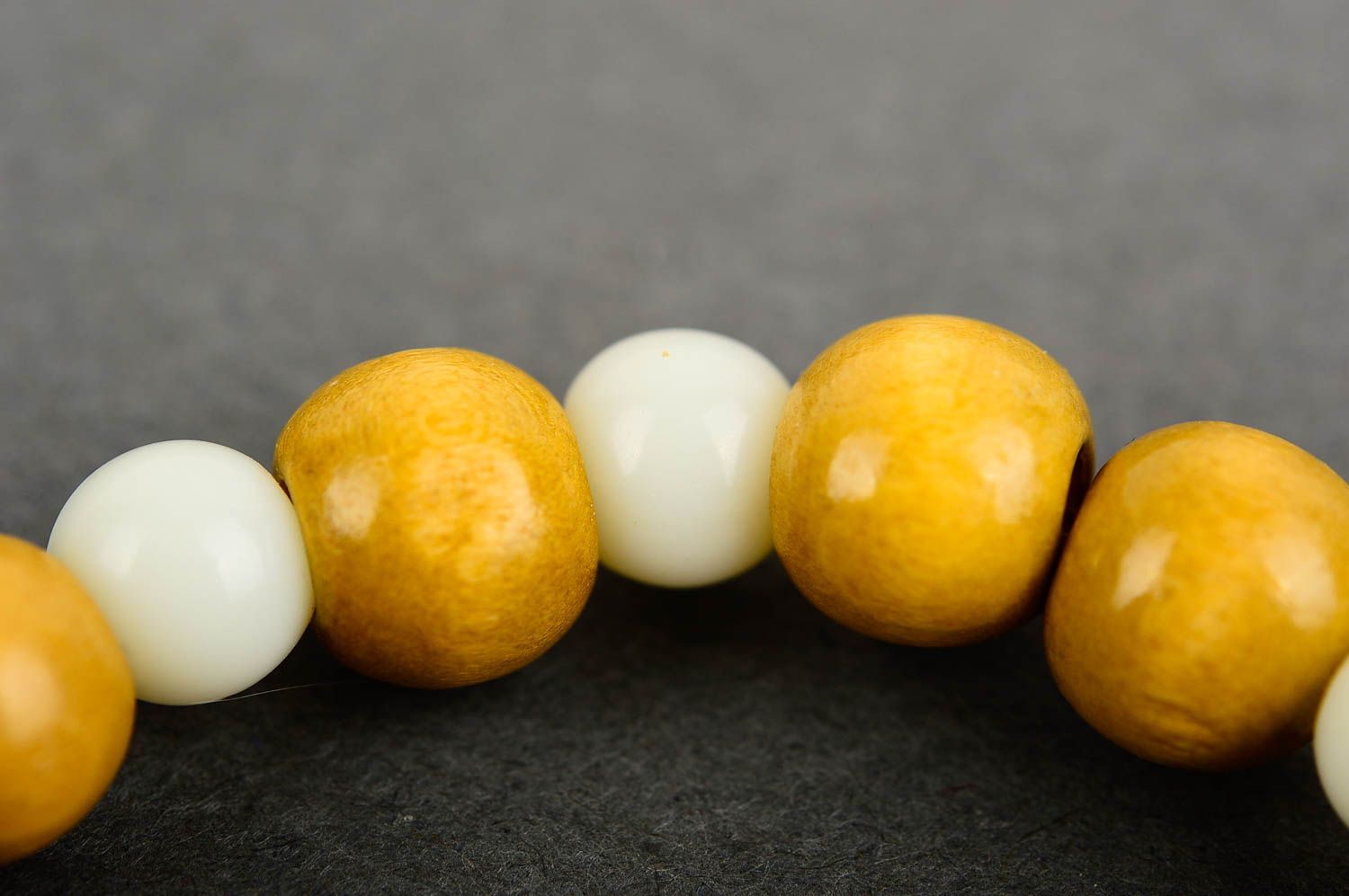 Stretchy beaded bracelet made of yellow wooden and white plastic beads photo 4